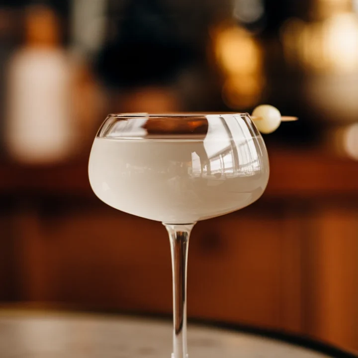 Elegant Gibson cocktail in a coupe glass with a pearl onion garnish on marble table.